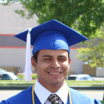 A male student wearing graduation gown, smiling
